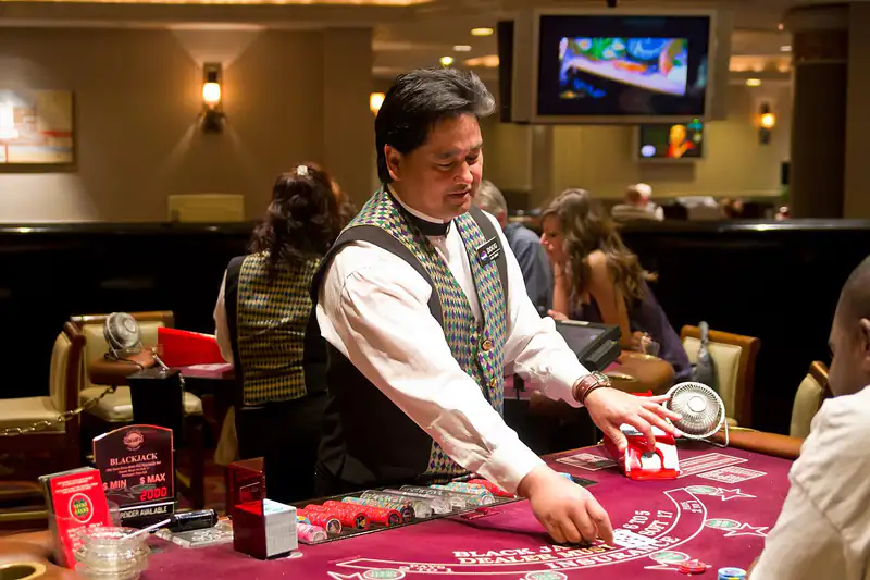 A dealer in a waistcoat running a card table while guests stand around watching the game