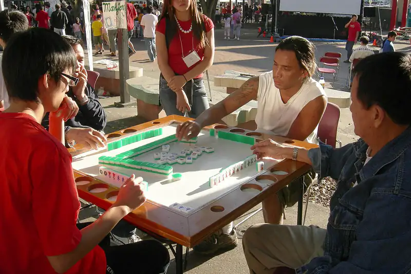 Friends playing mahjong together at a night market table