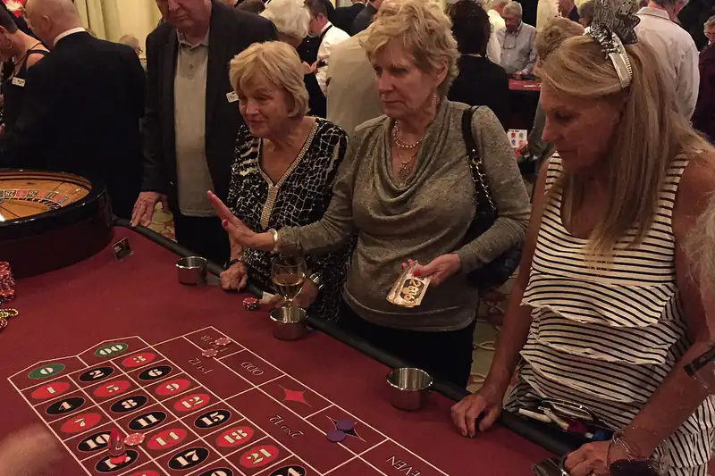 Women placing chips on a roulette table at a casino night